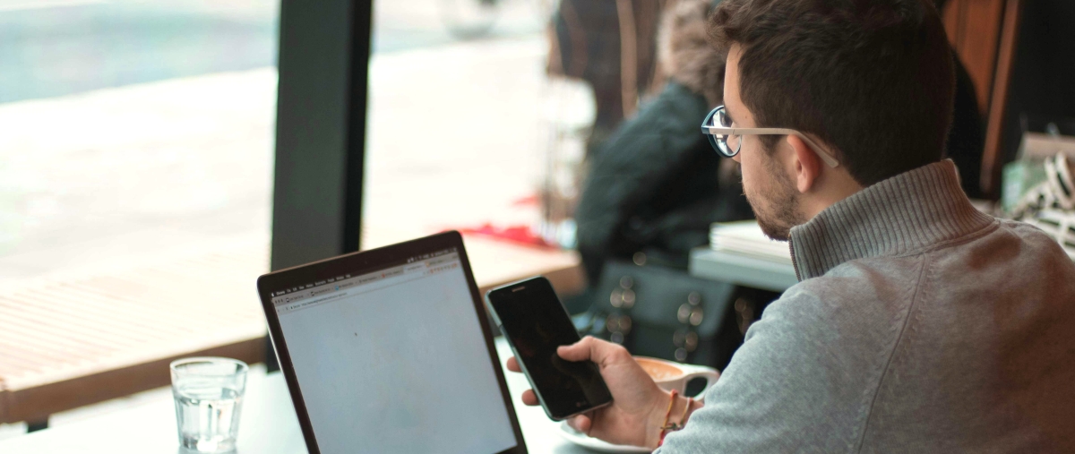 Erfahrungsberichte - Mann arbeitet in Cafe am Laptop